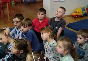 Dzieci oglądają przedstawienie siedząc naprzeciwko nauczycielki