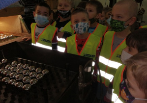 Chłopcy stoją przy maszynie i oglądają proces suszenia bombek