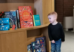 Chłopiec stoi przy ekspozycji książek