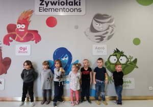 Dzieci stoja przy tablicy z zywiolami