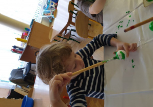 Chłopiec maluje bombkę na zielono