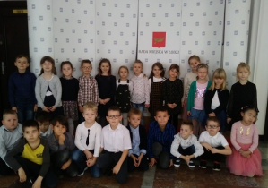 Zdjęcie grupowe. Dzieci stoją przy vanerze UrAd miasta Łodzi