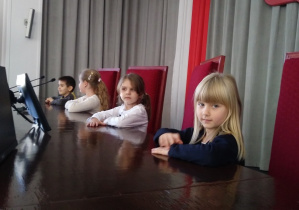 Dzieci siedzą za biurkiem w sali glownej