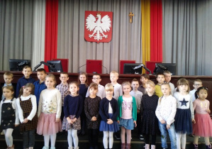 Dziecivstoja w grupie przed godłem polski