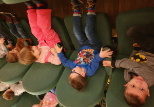 Dzieci siedzą na fotelach w kinie i czekają na bajkę