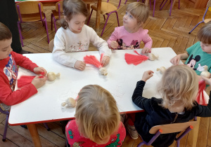 Dzieci siedzą przy stole i pracują według instrukcji nauczyciela