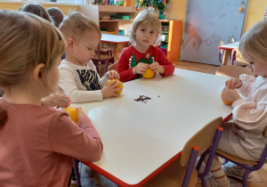 Dzieci siedzą przy stole i wykonują stroik