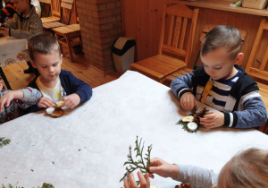 Chłopcy przy stole wykonują stroik świąteczny 