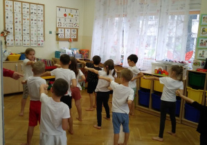 Dzieci stoją i ćwiczą według instrukcji