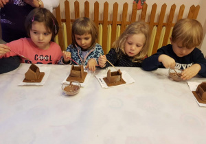 Dzieci sklejają elementy domku piernikowego