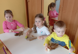 Dzieci siedzą przy stole I pracuja