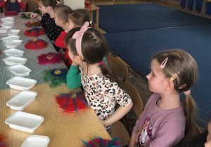 Dzieci siedzą przy stole I uczestniczą w warsztatach