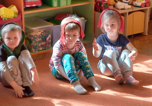 Dzieci siedzą na dywanie I wykonują ćwiczenie