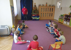 Dzieci siedzą na dywanie i Pani gra na tamburynie