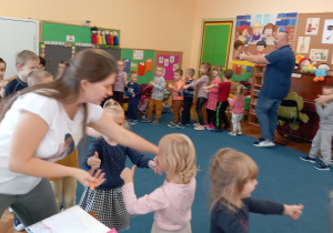 Dzieci stoją w kole naśladując ruchy prowadzacego