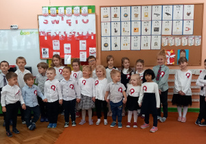 Dzieci stoją w grupie na baczność i śpiewają hymn Polski