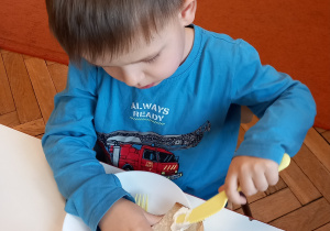Chłopiec smaruje kanapkę masłem