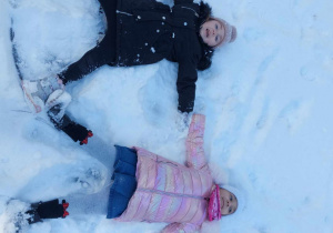 dwie dziewczynki robią aniołki na śniegu