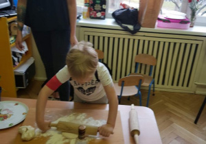 Chłopiec wałkuje ciasto na pizze