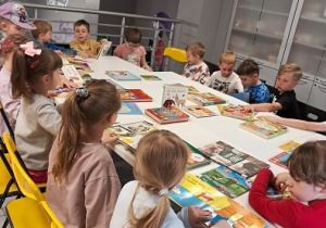 Dzieci siedzą w bibliotece przy stole