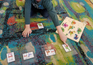 Chłopiec na dywanie i wskazuje obrazek dinozaura