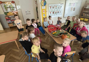 Dzieci siedzą i ogladaja warzywa