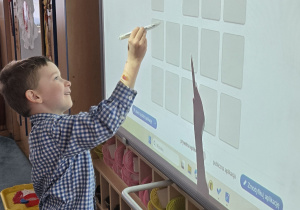 Chłopiec stoi przy tablicy