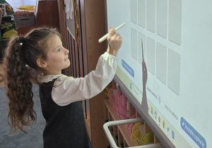 Dziewczynka stoi przy tablicy