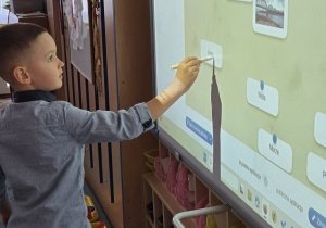 Chłopiec stoi przy tablicy