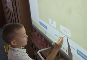 Chłopiec stoi przy tablicy