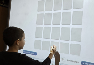 Chłopiec przy tablicy multimedialnej