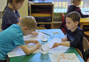 Dzieci robią przy stolikach prace plastyczne