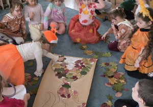 Dzieci wyklejają liśćmi Panią jesień