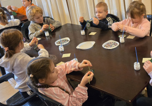 Dzieci przy stole dekorują bomkbę