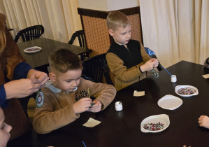 Dzieci przy stole dekorują bomkbę