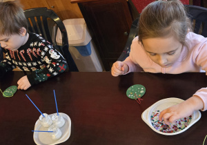 Dzieci przy stole dekorują bomkbę