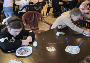 Dzieci przy stole dekorują bomkbę