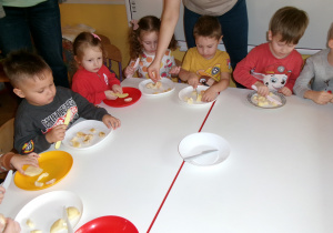 Przedszkolaki przygotowujące sałatkę owocową.