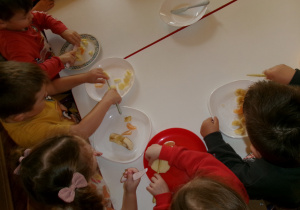 Przedszkolaki przygotowujące sałatkę owocową.