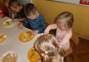 Przedszkolaki przygotowujące sałatkę owocową.