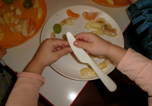 Przedszkolaki przygotowujące sałatkę owocową.