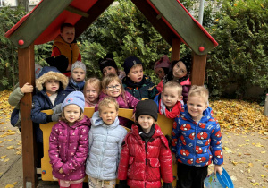 Posprzątane w ogródku. Dzieci stoją w domku