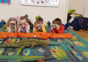 Dzieci oglądają dziką przyrodę przez zrobione przez siebie lornetki z rolek po papierze