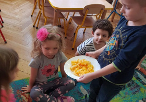 Chłopiec daje do powąchania dzieciom obranego pomarańcza