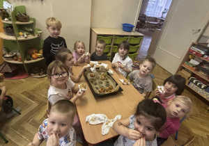 Dzieci przy stole jedzą pieczone jabłka