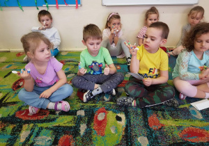 Dzieci biorą udział w teatrzyku paluszkowym na dywanie