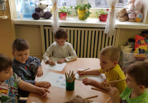 Chłopcy siedzą przy stole i kolorują obrazki zwierząt