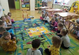 Dzieci siedzą na dywanie i oglądają matę do kodowania