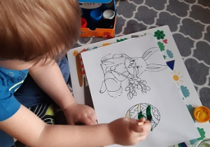 Chłopiec maluje farbami obrazek pisanki