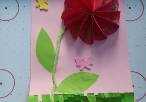 Kwiatek origami z kółek czerwonych przyklejony na kartkę